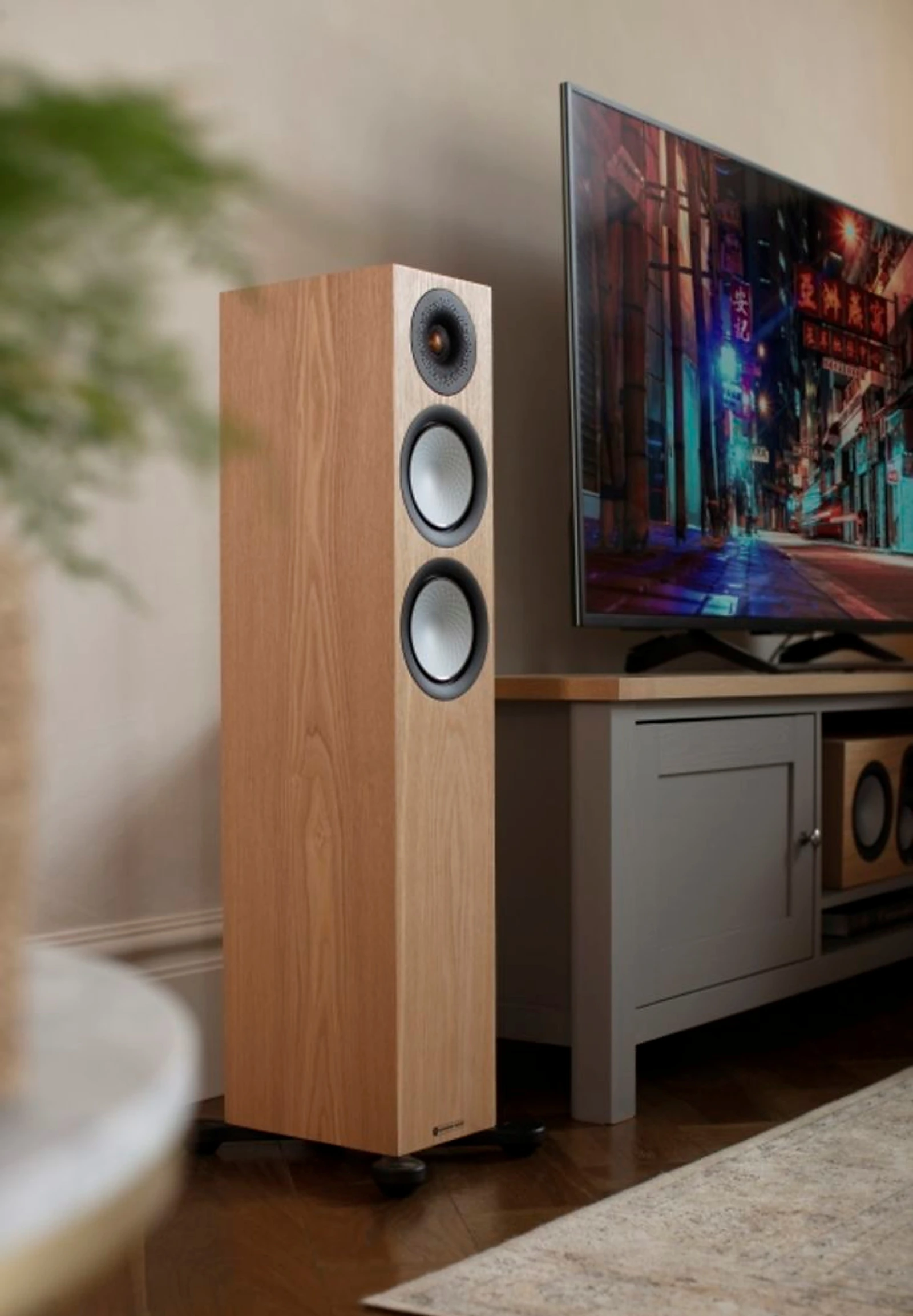 Monitor Audio floorstanding speaker beside a television in a living room